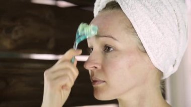 güzel kadın kozmetik prosedürler içinde ev işi havlu. yüz masaj masaj aleti ile