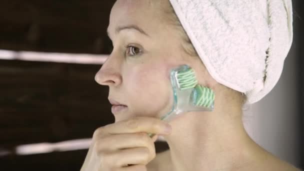 Bella donna in asciugamano facendo procedure cosmetiche in casa. massaggio viso con massaggiatore — Video Stock