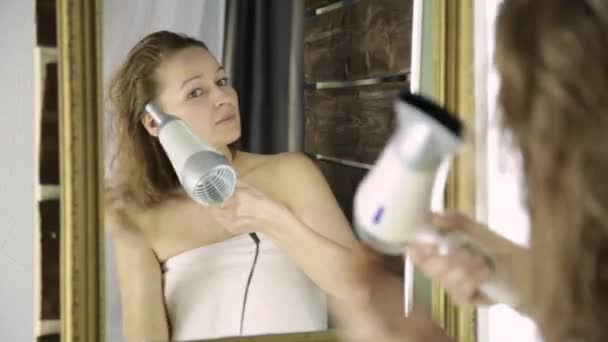 Молодая женщина в полотенце вытирает волосы перед зеркалом. Уход за кожей и дома Spa — стоковое видео