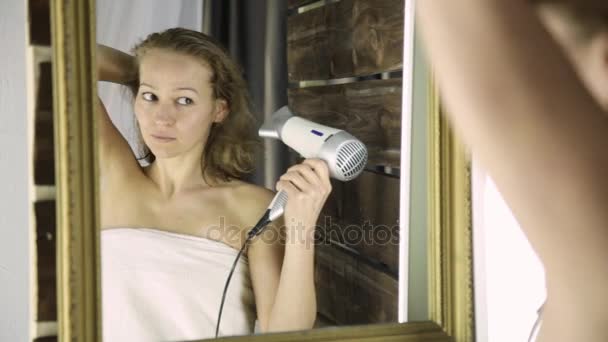 Молодая женщина в полотенце вытирает волосы перед зеркалом. Уход за кожей и дома Spa — стоковое видео