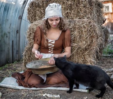 rustik giysili bir güzel kadına bir saman üzerinde oturur ve tahıl sifts