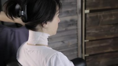 Kuaför istemci bir saç modeli için hazırlar. Kız müşteri bir güzellik salonu bir koltukta oturur