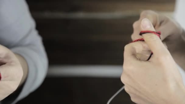 Close-up hands with knitting needles, old woman knits and granddaughter is studying — Stock Video