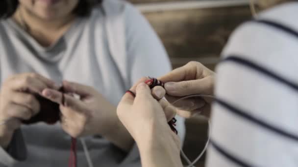 Close-up hands with knitting needles, old woman knits and granddaughter is studying — Stock Video