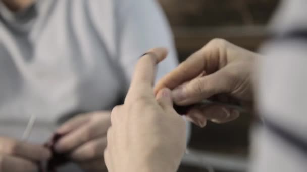 Primer plano manos con agujas de punto, anciana teje y nieta está estudiando — Vídeo de stock