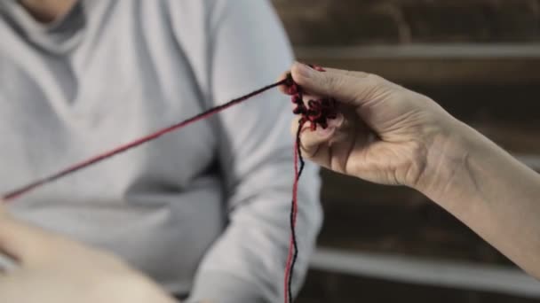 Detail rukou s pletací jehlice, stará žena plete a vnučka studuje — Stock video