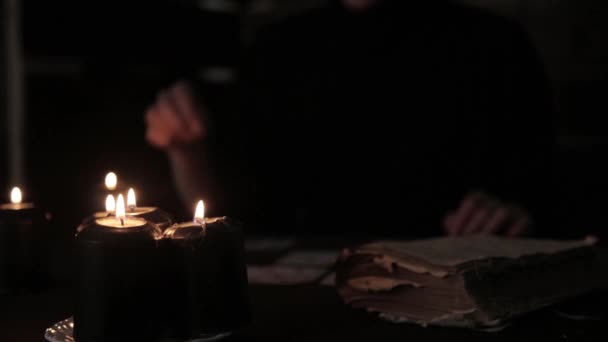 Mystique belle femme dans une robe noire, divination sur les cartes à la chandelle — Video