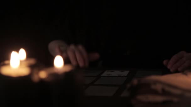 Mystique belle femme dans une robe noire, divination sur les cartes à la chandelle — Video