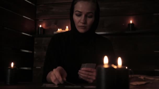 Monja hermosa mística en un vestido negro, adivinación en tarjetas con velas negras — Vídeos de Stock