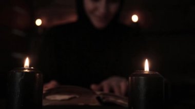 siyah elbiseli mistik güzel Rahibe, Rahibe siyah mum ışığı ile eski bir kitap okur.