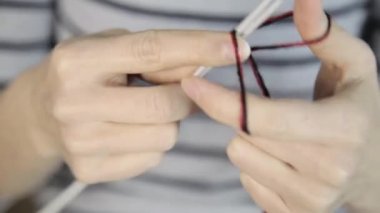 Örgü iğneleriyle yakın çekim eller, güzel bir kadın örgü örer.