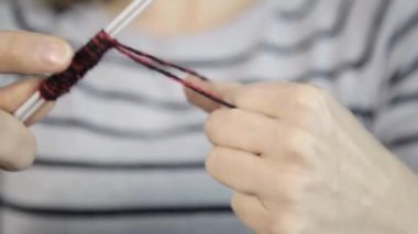 Örgü iğneleriyle yakın çekim eller, güzel bir kadın örgü örer.