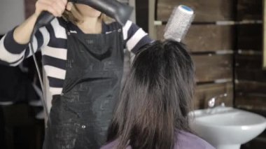 Profesyonel kuaför saç şekillendirme için güzel kadın müşteri yapar ve saç kurutma makinesi tarağı ile kullanılan