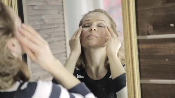 Красива жінка масажує голову перед дзеркалом із закритими очима — стокове відео