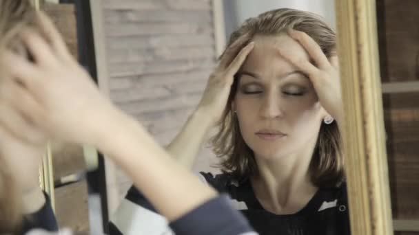 Bela mulher massagens sua cabeça na frente do espelho com fechar seus olhos — Vídeo de Stock