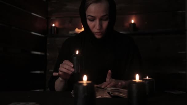 Bella suora tiene una candela e la lettura di un vecchio libro di mette in evidenza la fiamma. Concetto di cristianesimo — Video Stock