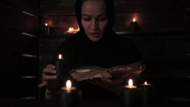 Belle religieuse tient une bougie et la lecture de vieux livre de faits saillants de la flamme. Concept de christianisme — Video