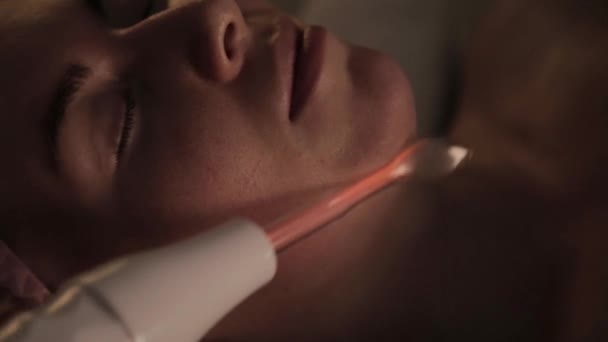 Vacker kvinna har en elektrisk darsonval massage förfarande i en mörk — Stockvideo