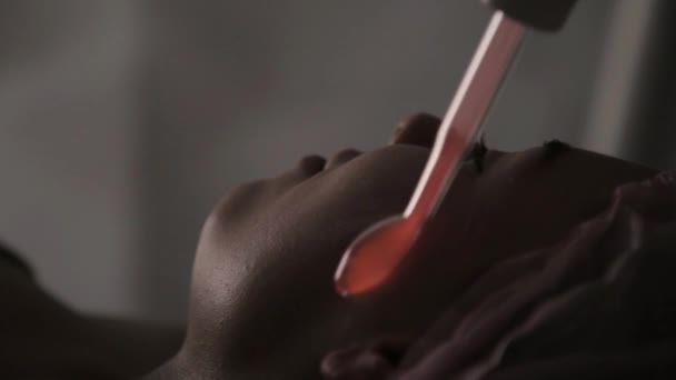 Косметолог робить електричну процедуру масажу Дарсонваль для жіночого клієнта в темряві — стокове відео