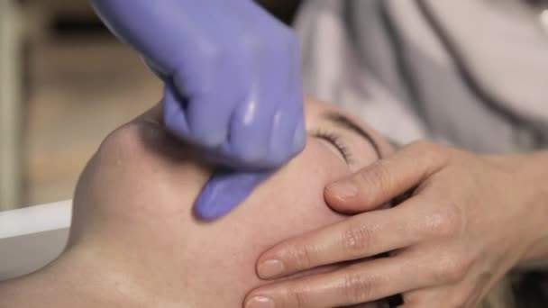 Контурный пластик. косметолог делает массаж губ красивой женщине в салоне красоты — стоковое видео
