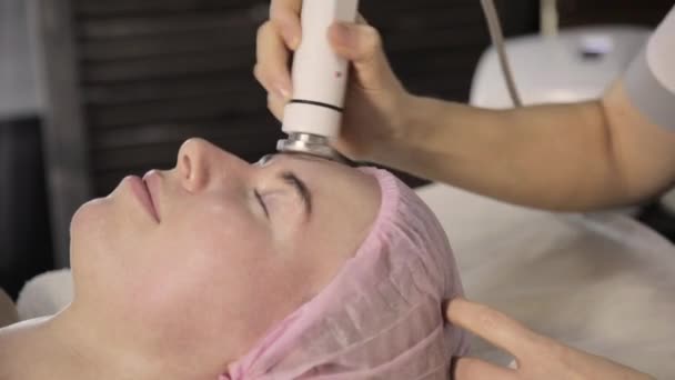 Косметик делает процедуру подтяжки лица для женщины в салоне красоты. Аппаратная косметология — стоковое видео