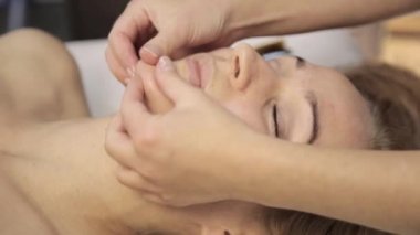 masör acupressure bir kadın yüzü üzerinde yapar. Çin alternatif tıp