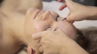 masör acupressure bir kadın yüzü üzerinde yapar. Çin alternatif tıp
