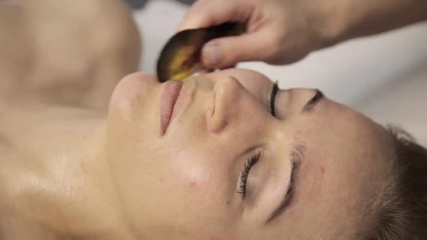 Belle femme a une acupression sur un visage avec gouache racleur. Médecine alternative chinoise — Video