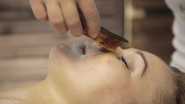 masör acupressure bir kadın yüzü üzerinde yapar. Çin alternatif masajı ile sıyırıcı guaş