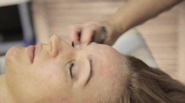 masör acupressure bir kadın yüzü üzerinde yapar. Çin alternatif masajı ile sıyırıcı guaş