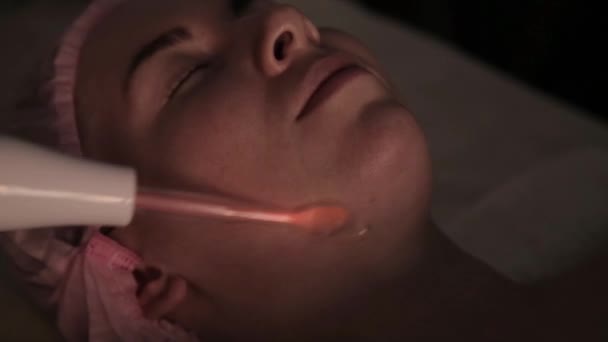 Schoonheidsspecialiste doet elektrische darsonval massage procedure voor vrouwelijke client in een donker — Stockvideo