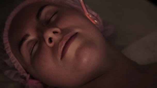 Kozmetikus csinál elektromos darsonval masszázs eljárás női ügyfél egy sötét — Stock videók