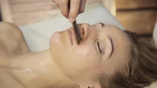 Acupression sur un visage féminin. Massage alternatif chinois à la gouache racleur — Video