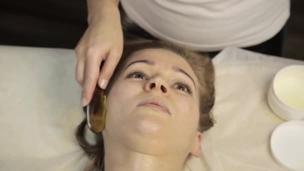 Acupressuur op een vrouwelijk gezicht. Chinese alternatieve massage met schraper gouache — Stockvideo