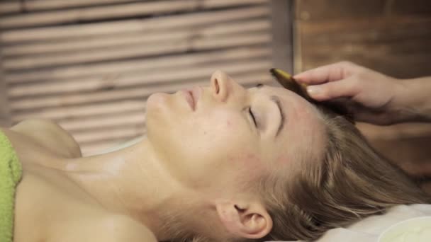 Massagista faz acupressão em um rosto feminino. Massagem alternativa chinesa com guache raspador — Vídeo de Stock