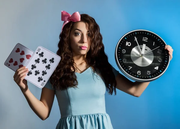 Hermosa chica pinup en un vestido azul sosteniendo gran reloj sobre un fondo azul —  Fotos de Stock