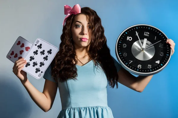 Hermosa chica pinup en un vestido azul sosteniendo gran reloj sobre un fondo azul —  Fotos de Stock