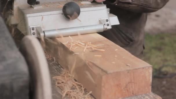 Людина працює на дерев'яній машині. Чіпси літають в іншу сторону від стругача — стокове відео