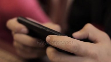 Yakın çekim çocuk elleri ile bir telefon, oynamak için onun smartphone kullanarak genç