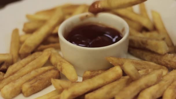 Sumergiendo papas fritas en una pequeña taza de ketchup — Vídeo de stock
