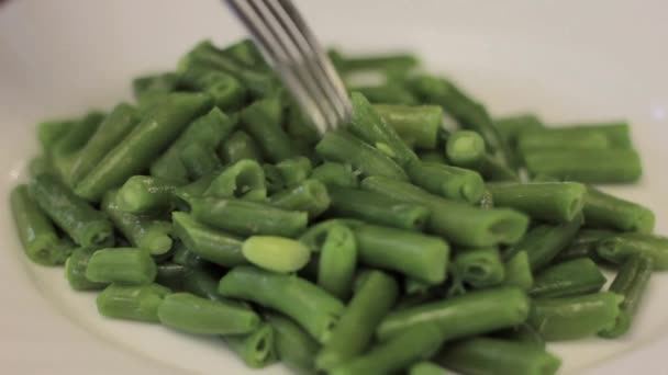 Eating cooked green beans with fork on a white plate — Stock Video