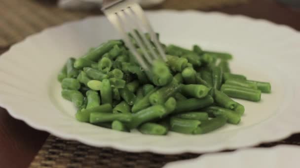 흰색 접시에 포크와 함께 녹색 콩 요리 먹고 — 비디오