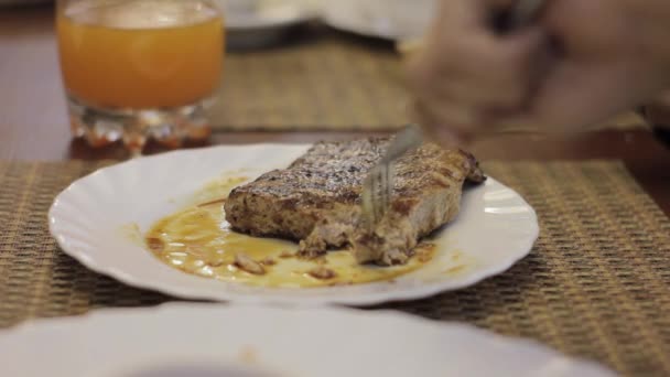 Snijden gebraden rundvlees op een witte plaat, tiener eet vlees in een café — Stockvideo