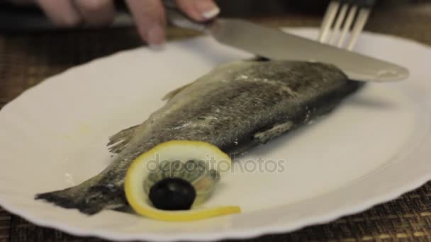 女人吃鱼与他的手在一个白色的盘子在咖啡馆 — 图库视频影像