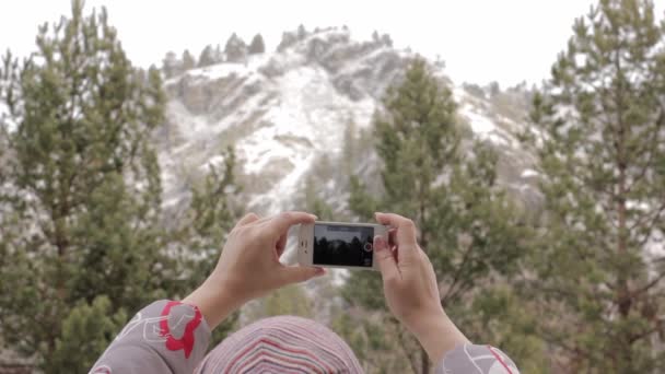 Ung kvinnlig turist tar bilder berg och tallar på sin smartphone — Stockvideo