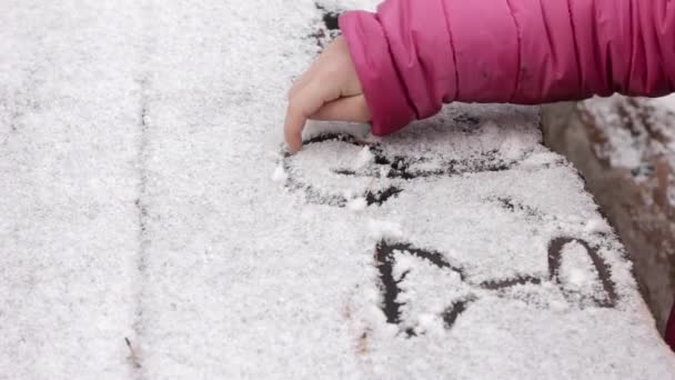 Jong meisje tekenen op een besneeuwde tafel, kinderen spelen in een winter-hout — Stockvideo