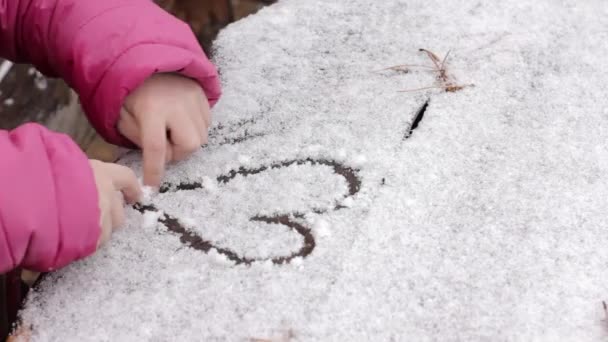 Junges Mädchen zeichnet auf einem schneebedeckten Tisch, Kinderspiele im Winterwald — Stockvideo