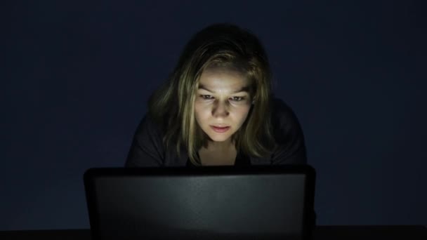 Frau mit Brille bedient Computer in einem dunklen Raum, blickt auf den Monitor und fängt an zu jubeln — Stockvideo