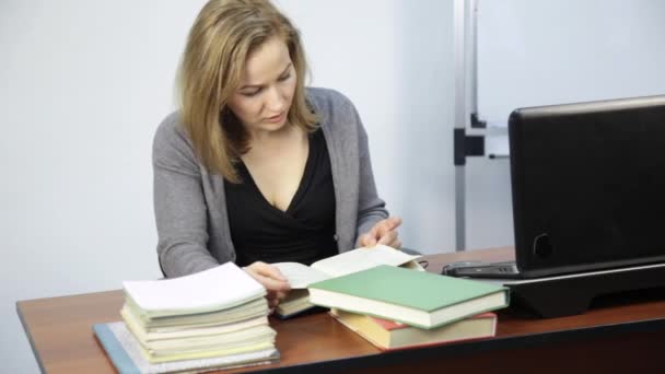 Vrouwelijke student leest het boek aan de voorzijde van de laptop — Stockvideo