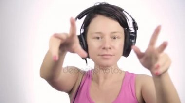 Güzel kadın hafif bir arka plan üzerinde bir müzik dinlerken kulaklık dans